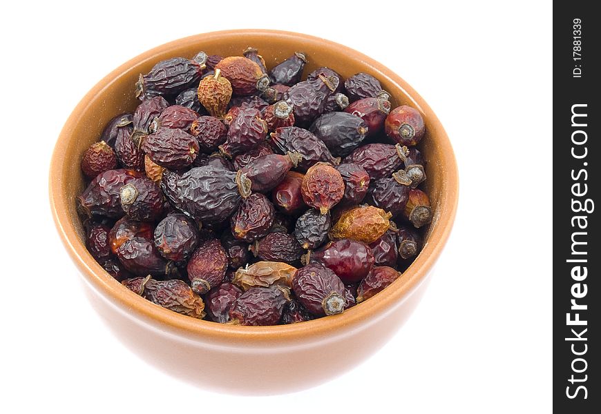 The plate is filled by dry berries of a dogrose is on a white background. The plate is filled by dry berries of a dogrose is on a white background