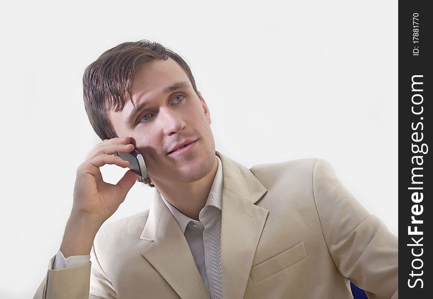 A young man in the office sitting on a chair and talking on the phone. A young man in the office sitting on a chair and talking on the phone