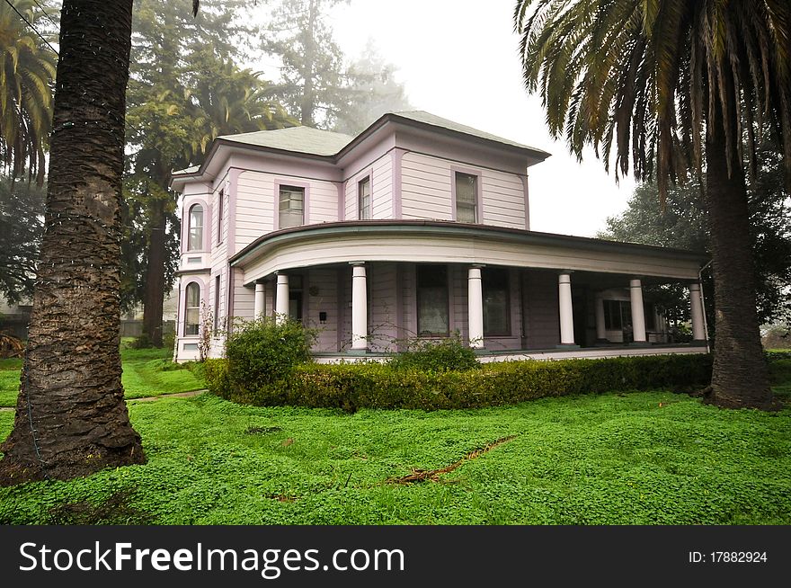 House surrounded by trees and grass with foggy sky.