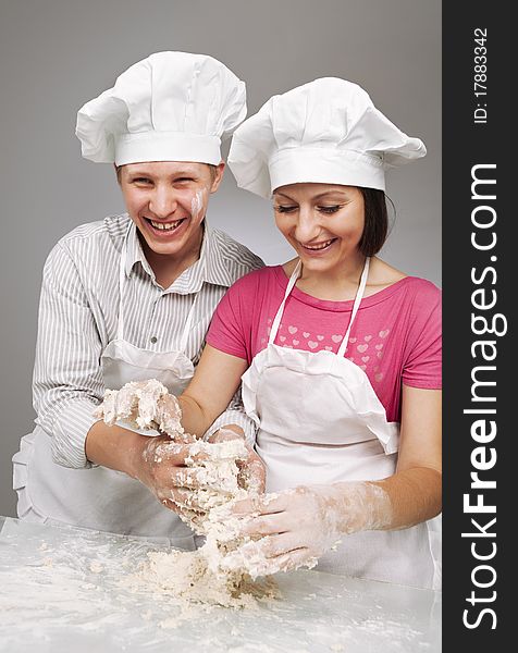 Young loving couple playing with dough. Over grey background