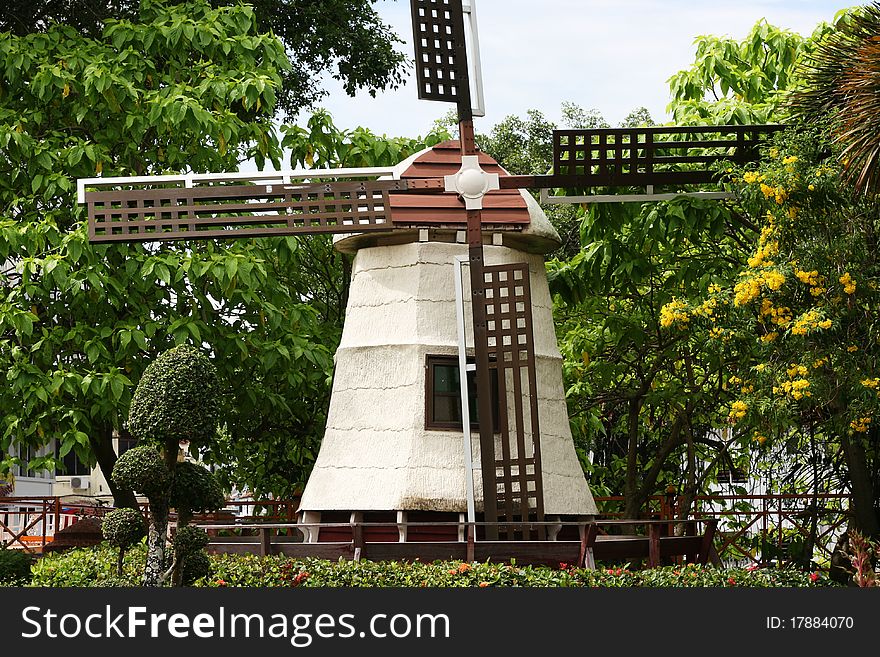 A windmill in a country scene. The windmill is surrounded by colorful plants. A windmill in a country scene. The windmill is surrounded by colorful plants.