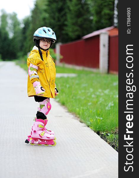 Adorable little girl in yellow raincoat, blue helmet and pink roller skates. Adorable little girl in yellow raincoat, blue helmet and pink roller skates