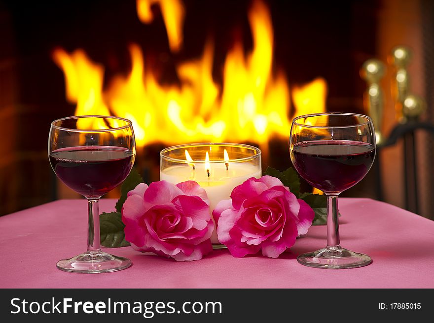 Two glasses of wine on a table with a fireplace in the background. Two glasses of wine on a table with a fireplace in the background.