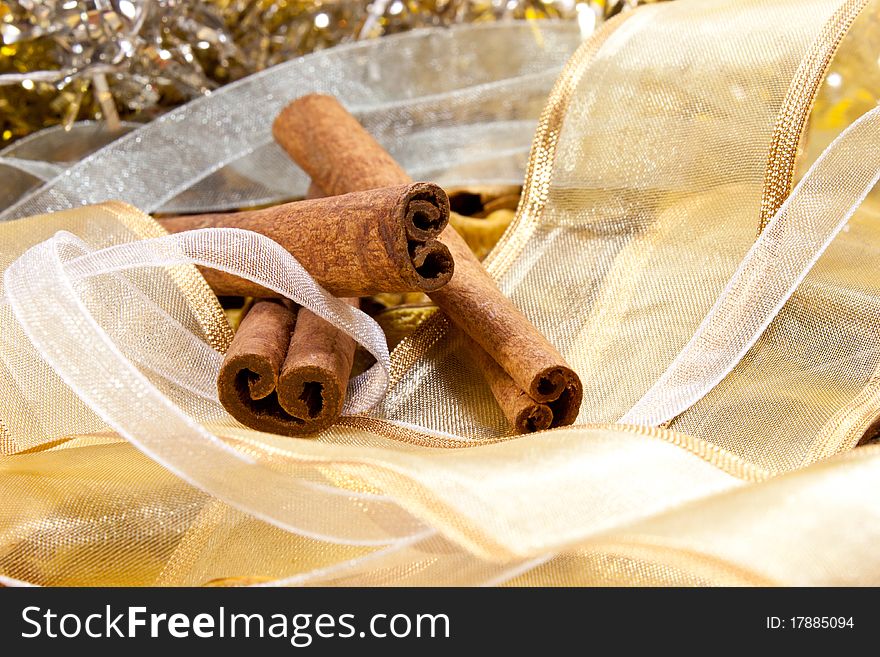 Cinnamon on random background with white and gold ribbons. Cinnamon on random background with white and gold ribbons