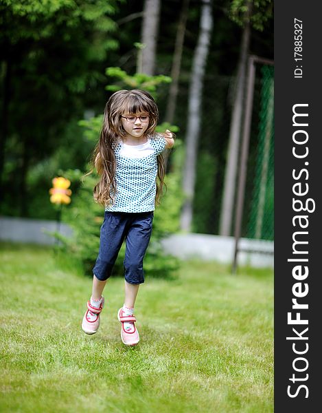 Adorable active little girl with long dark hair plays on backyard in spring