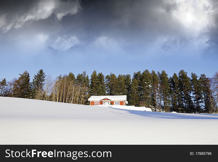 Small red farm in wintery sweden, snow and ice, dark clouds on horizon. Small red farm in wintery sweden, snow and ice, dark clouds on horizon