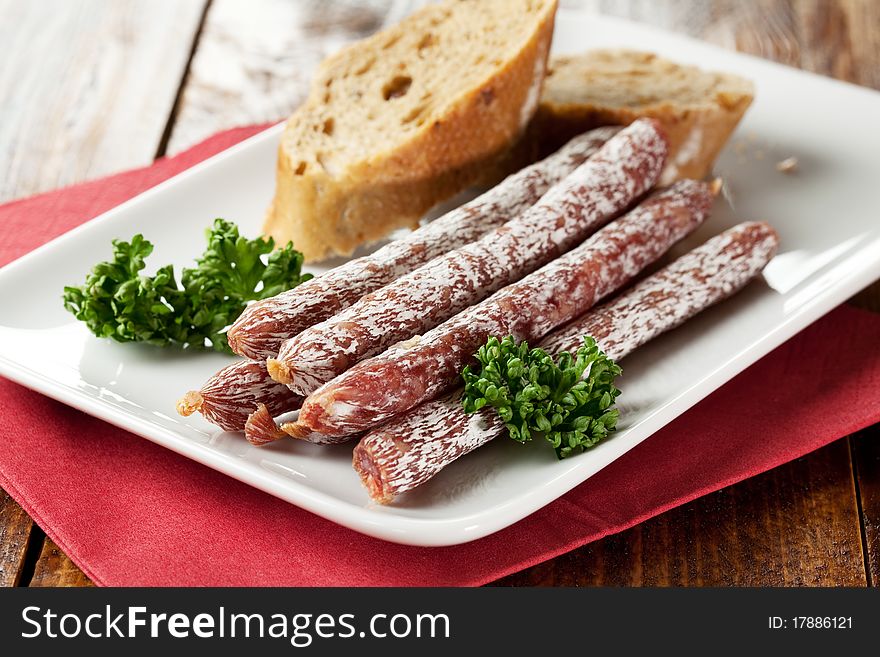 Small salamis on plate with bread and parsley. Small salamis on plate with bread and parsley