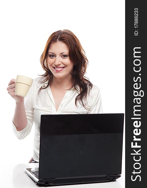 Beautiful smiling girl sitting at table with laptop and cup, isolated on white