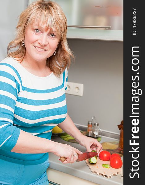 Beautiful woman in the kitchen cutting vegetables. Beautiful woman in the kitchen cutting vegetables