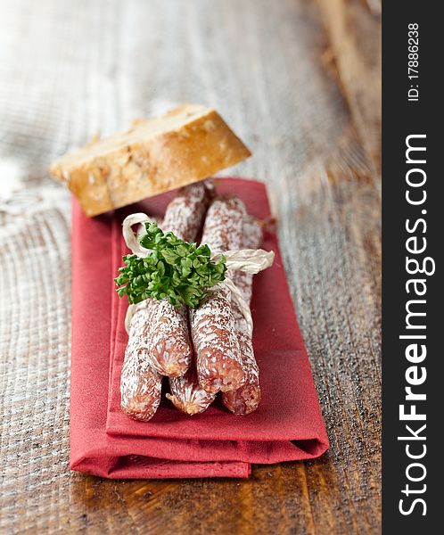 Small salamis on napkin with bread (country style)