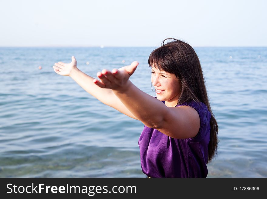 Beautiful young woman opened her hands with delight at the blue sky and sea. Beautiful young woman opened her hands with delight at the blue sky and sea