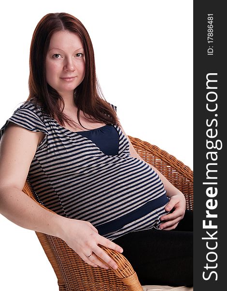 Pregnant woman sitting on a wicker chair , isolated on white