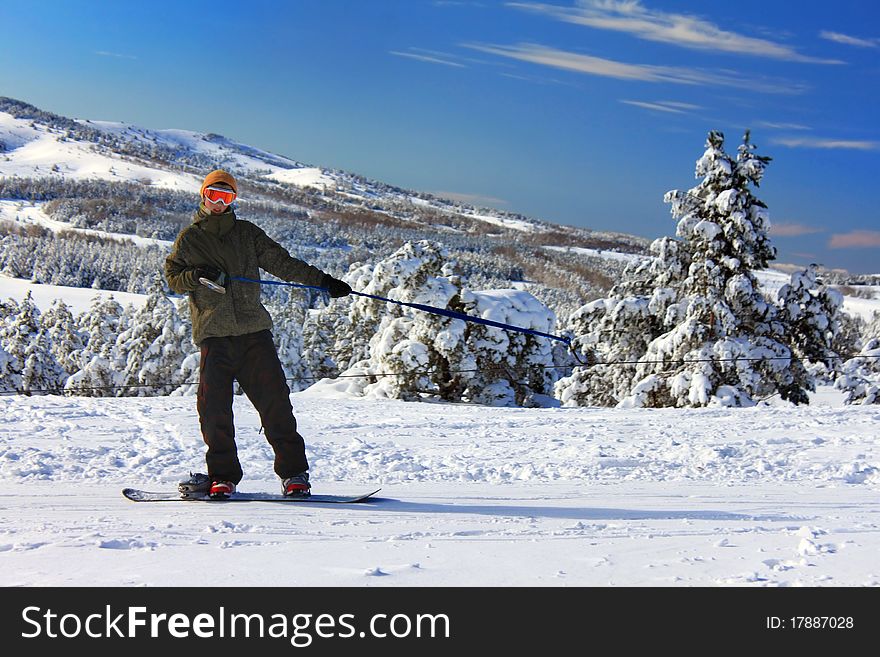Snowboarder on the slope rises up against the backdrop of snow-covered trees