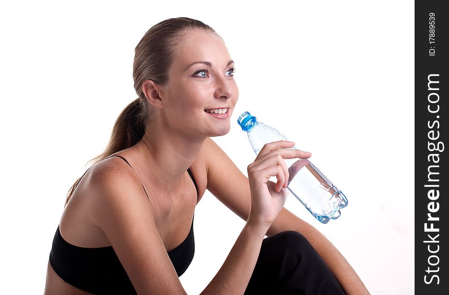 Woman in fitness pose holding water bottle, studio shot