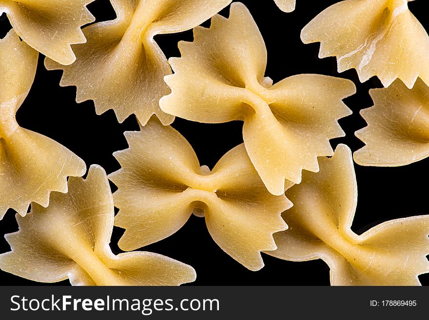 Pasta, spaghetti, shells, rings, bows on a black or white background top view.