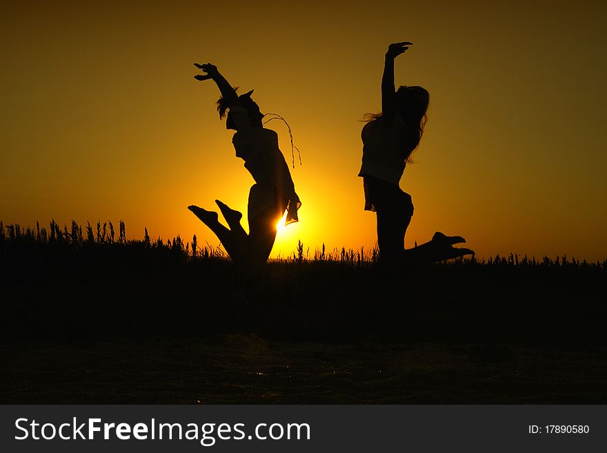 Two women in silhouette jumping happily in the sunset. Two women in silhouette jumping happily in the sunset