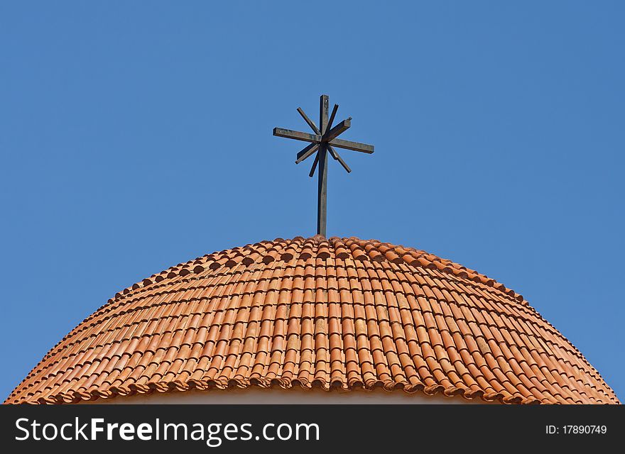 Round roof of a church - covered with tiles and cross