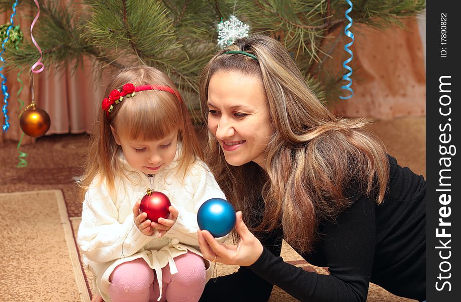 Mom and girl near christmas tree with balls. Mom and girl near christmas tree with balls