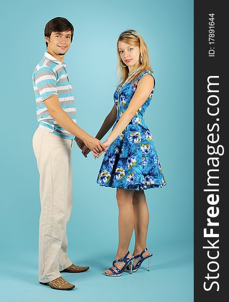 Loving couple holding hands against the blue background