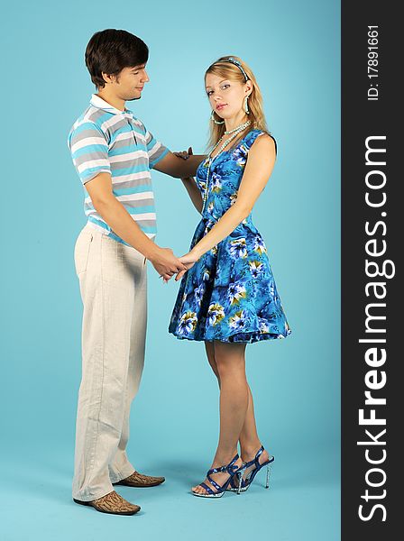 Loving couple holding hands against the blue background