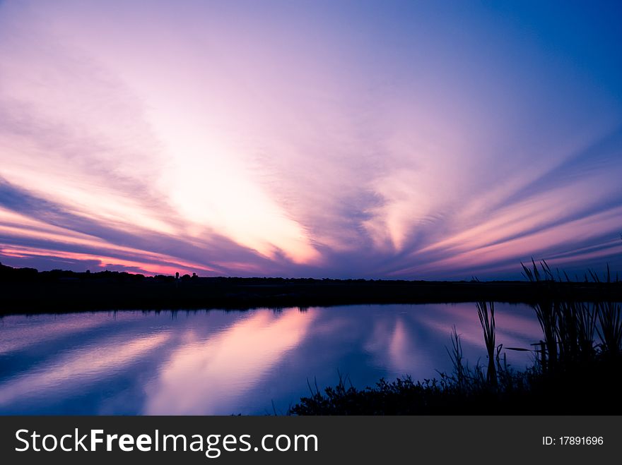 Dramatic sky after sunset reflected in a pond. Zephyrhills dropzone, Florida, USA. Dramatic sky after sunset reflected in a pond. Zephyrhills dropzone, Florida, USA