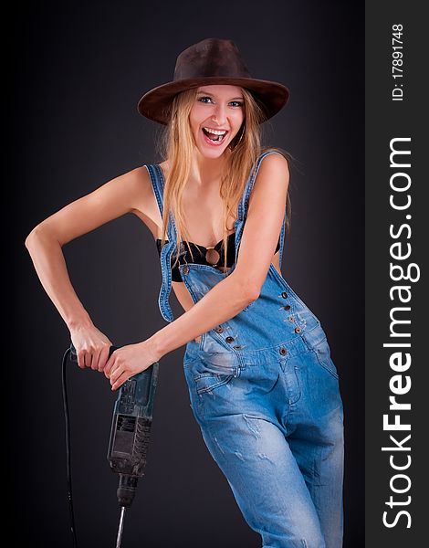 Girl with a drill in building overalls