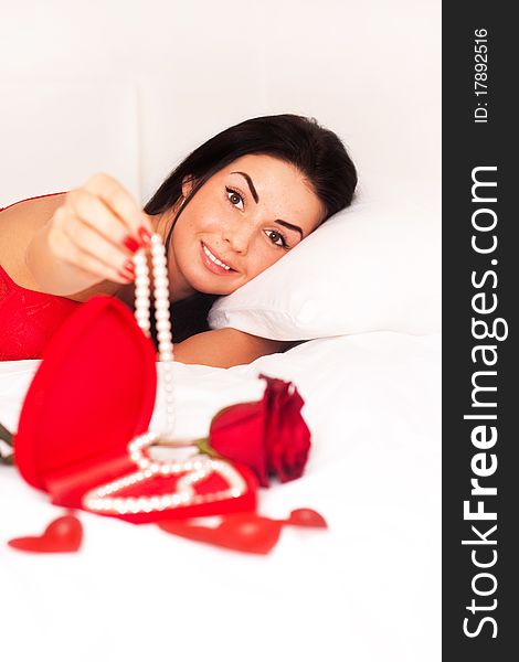 Girl lying in bed, strewn with hearts and roses