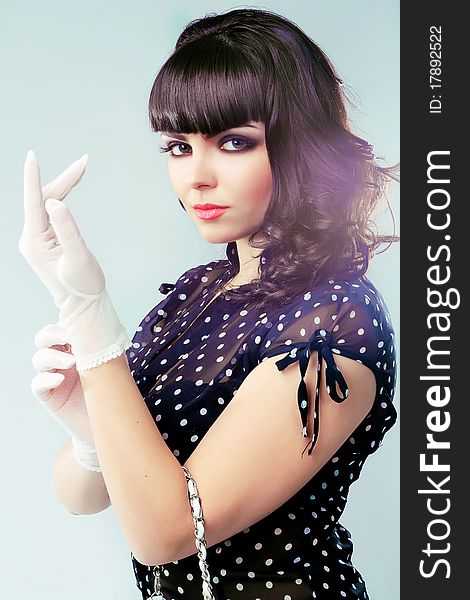 Studio portrait of a pretty elegant brunette dressing white gloves