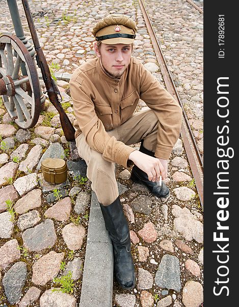 Soldier in uniform of World War I, sit down, resting on the pavement and smoking. Costume accord the times of World War I. Photo made at cinema city Cinevilla in Latvia. Cockade on the hat do not contain trade mark. Soldier in uniform of World War I, sit down, resting on the pavement and smoking. Costume accord the times of World War I. Photo made at cinema city Cinevilla in Latvia. Cockade on the hat do not contain trade mark.