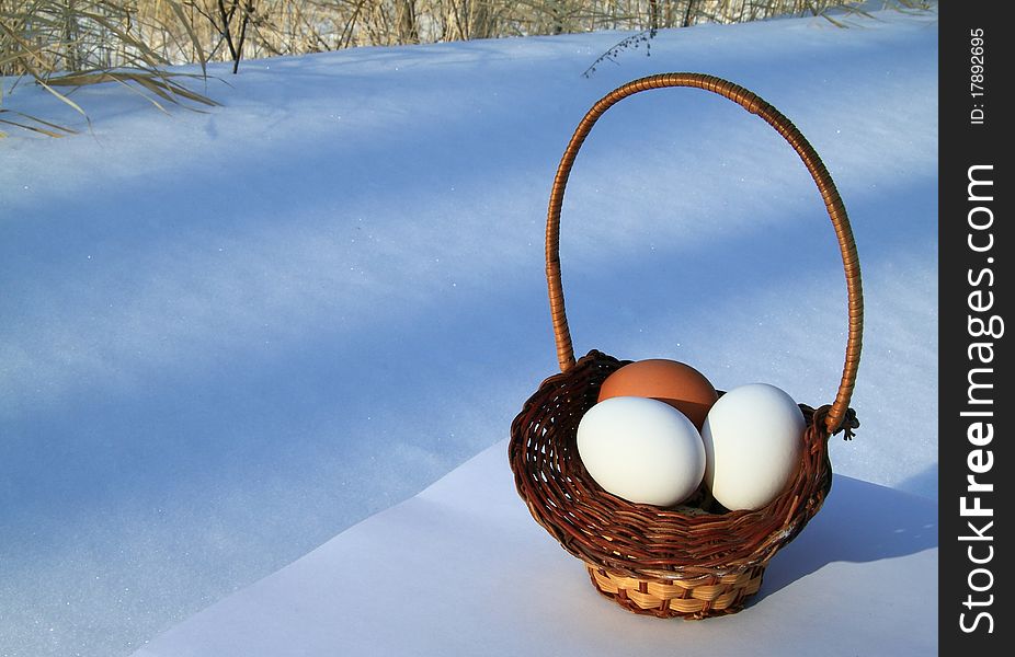 Three eggs in a basket on a background of a white snow