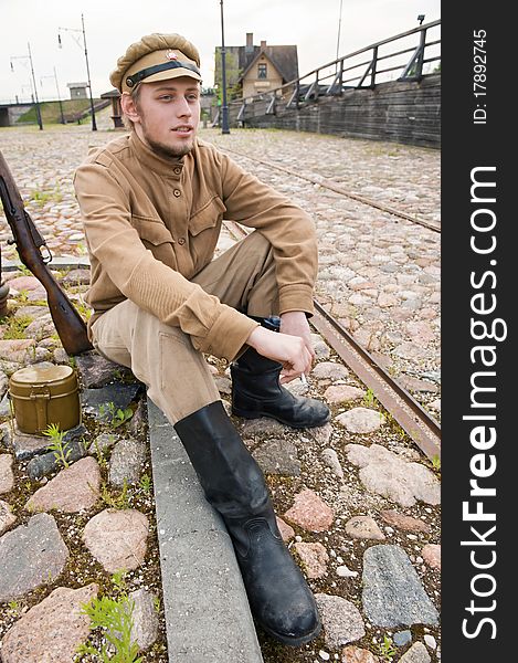 Soldier in uniform of World War I, sit down, resting on the pavement and smoking. Costume accord the times of World War I. Photo made at cinema city Cinevilla in Latvia. Cockade on the hat do not contain trade mark. Soldier in uniform of World War I, sit down, resting on the pavement and smoking. Costume accord the times of World War I. Photo made at cinema city Cinevilla in Latvia. Cockade on the hat do not contain trade mark.