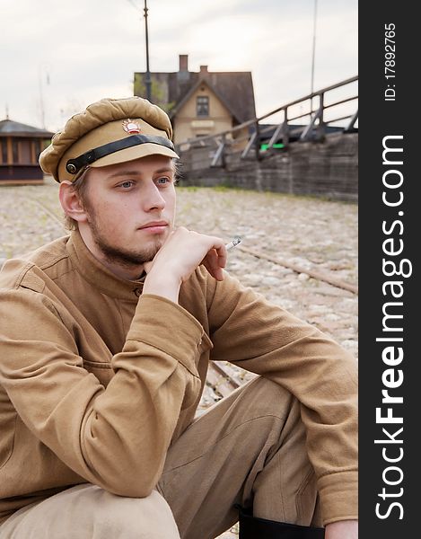 Soldier in uniform of World War I, sit down, resting on the pavement and smoking. Costume accord the times of World War I. Photo made at cinema city Cinevilla in Latvia. Cockade on the hat do not contain trade mark. Soldier in uniform of World War I, sit down, resting on the pavement and smoking. Costume accord the times of World War I. Photo made at cinema city Cinevilla in Latvia. Cockade on the hat do not contain trade mark.