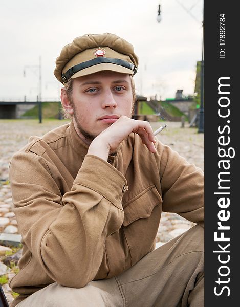 Soldier in uniform of World War I, sit down, resting on the pavement and smoking. Costume accord the times of World War I. Photo made at cinema city Cinevilla in Latvia. Cockade on the hat do not contain trade mark. Soldier in uniform of World War I, sit down, resting on the pavement and smoking. Costume accord the times of World War I. Photo made at cinema city Cinevilla in Latvia. Cockade on the hat do not contain trade mark.