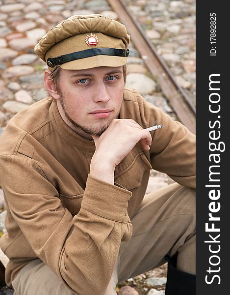 Soldier in uniform of World War I, sit down, resting on the pavement and smoking. Costume accord the times of World War I. Photo made at cinema city Cinevilla in Latvia. Cockade on the hat do not contain trade mark. Soldier in uniform of World War I, sit down, resting on the pavement and smoking. Costume accord the times of World War I. Photo made at cinema city Cinevilla in Latvia. Cockade on the hat do not contain trade mark.