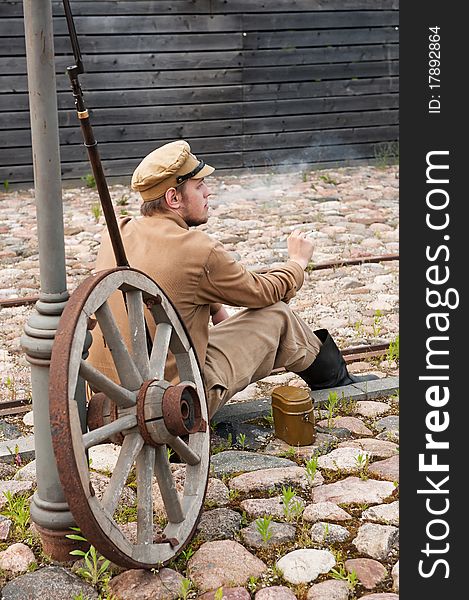 Soldier in uniform of World War I, sit down, resting on the pavement and smoking. Costume accord the times of World War I. Photo made at cinema city Cinevilla in Latvia. Soldier in uniform of World War I, sit down, resting on the pavement and smoking. Costume accord the times of World War I. Photo made at cinema city Cinevilla in Latvia.