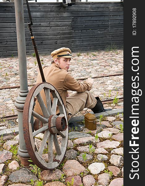 Soldier in uniform of World War I, sit down, resting on the pavement and smoking. Costume accord the times of World War I. Photo made at cinema city Cinevilla in Latvia. Soldier in uniform of World War I, sit down, resting on the pavement and smoking. Costume accord the times of World War I. Photo made at cinema city Cinevilla in Latvia.