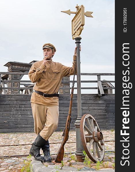 Soldier with a gun in uniform of World War I, smoking at tram stop. Costume accord the times of World War I. Photo made at cinema city Cinevilla in Latvia. Soldier with a gun in uniform of World War I, smoking at tram stop. Costume accord the times of World War I. Photo made at cinema city Cinevilla in Latvia.