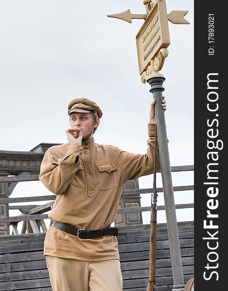 Soldier with a gun in uniform of World War I, smoking at tram stop. Costume accord the times of World War I. Photo made at cinema city Cinevilla in Latvia. Soldier with a gun in uniform of World War I, smoking at tram stop. Costume accord the times of World War I. Photo made at cinema city Cinevilla in Latvia.