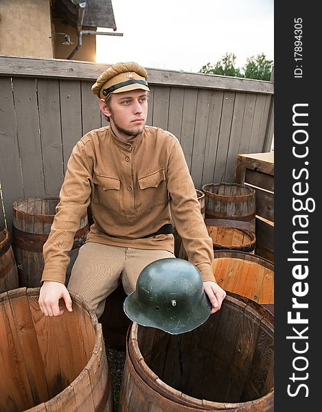 Soldier with a helmet sitting on the butt. Costume accord the times of World War I. Photo made at cinema city Cinevilla in Latvia. Soldier with a helmet sitting on the butt. Costume accord the times of World War I. Photo made at cinema city Cinevilla in Latvia.