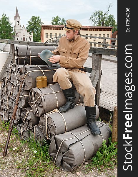 Soldier with helmet and gun sitting on the bundles. Costume accord the times of World War I. Photo made at cinema city Cinevilla in Latvia. Soldier with helmet and gun sitting on the bundles. Costume accord the times of World War I. Photo made at cinema city Cinevilla in Latvia.