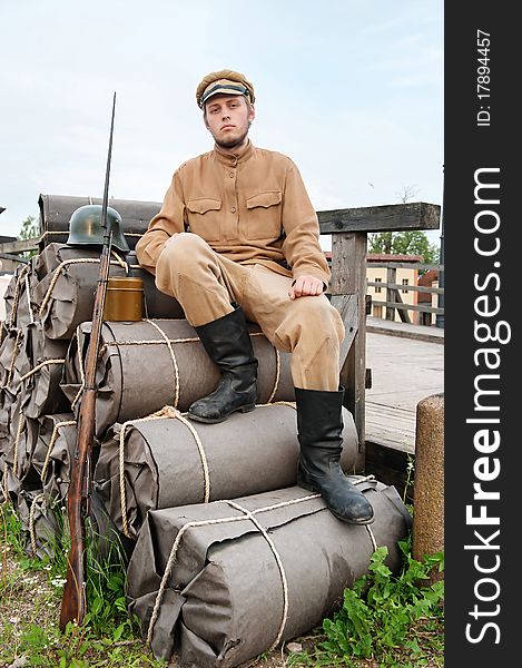 Soldier with helmet and gun sitting on the bundles. Costume accord the times of World War I. Photo made at cinema city Cinevilla in Latvia. Soldier with helmet and gun sitting on the bundles. Costume accord the times of World War I. Photo made at cinema city Cinevilla in Latvia.