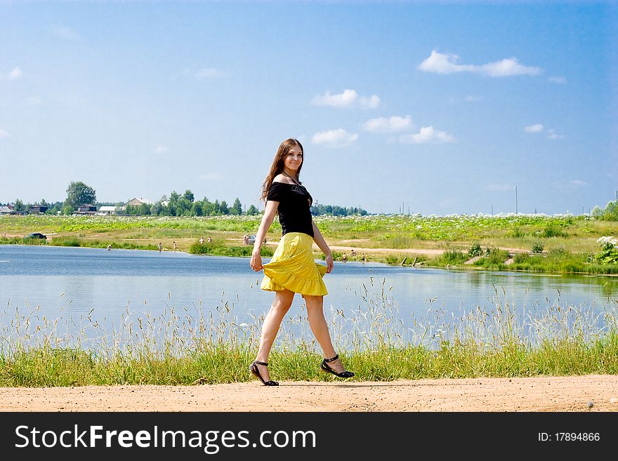 Woman walking near the lake on a sunny summer day. Woman walking near the lake on a sunny summer day