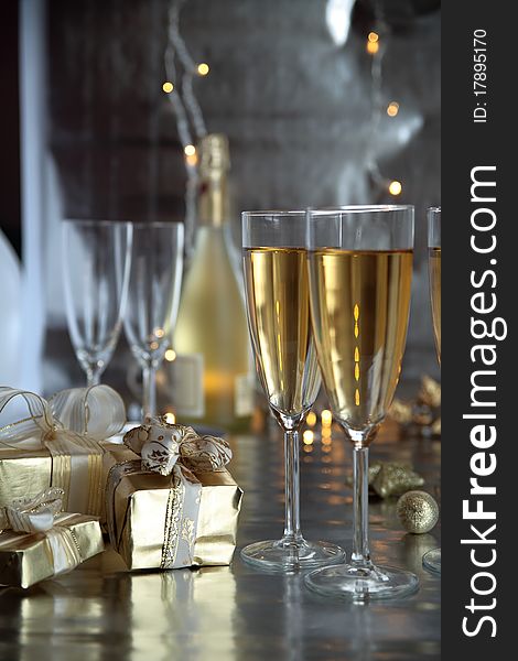 Champagne in glasses and gifts, blured lights on background.