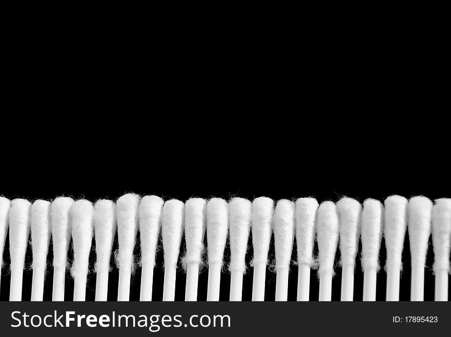 Line of white cotton buds isolated on black background