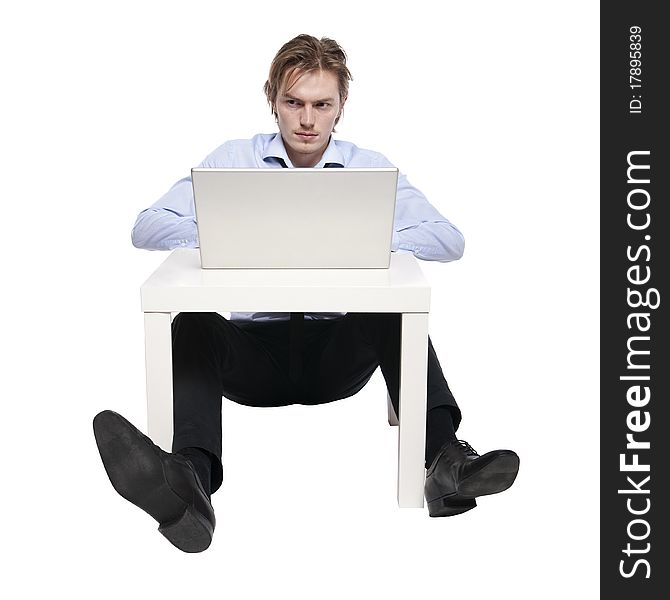 Young businessman, office worker or student with laptop, Studio photo of young man sitting at funny small table. Young businessman, office worker or student with laptop, Studio photo of young man sitting at funny small table.