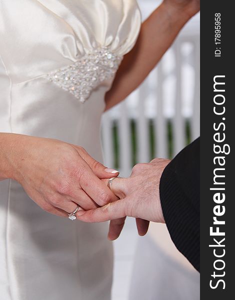 Husband and wife's hands with wedding ring. Bride puts silver band on grooms finger. Husband and wife's hands with wedding ring. Bride puts silver band on grooms finger.