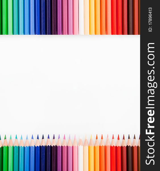 Top view of colored pencils with free, white place in the middle