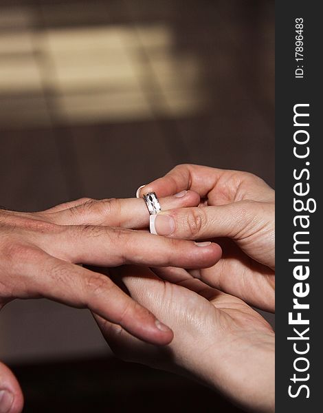 Husband and wife's hands with wedding ring. Bride puts silver band on grooms finger. Husband and wife's hands with wedding ring. Bride puts silver band on grooms finger.