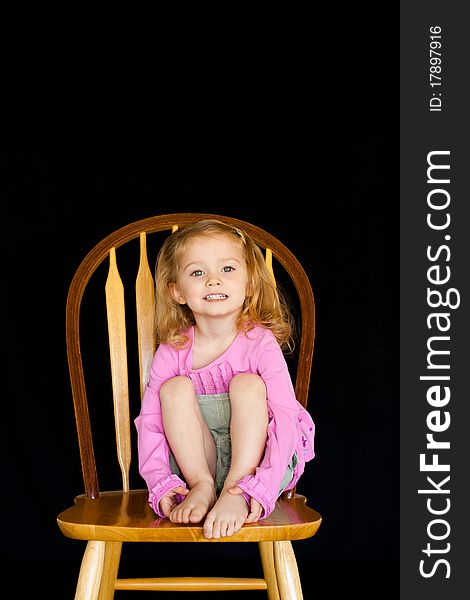 A cute girl sitting on a chair/stool.  She has a very unique facial expression. A cute girl sitting on a chair/stool.  She has a very unique facial expression.