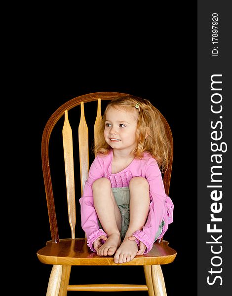 A cute girl sitting on a chair/stool. She has a very unique facial expression. A cute girl sitting on a chair/stool. She has a very unique facial expression.